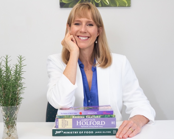 Woman with books, smiling at camera.